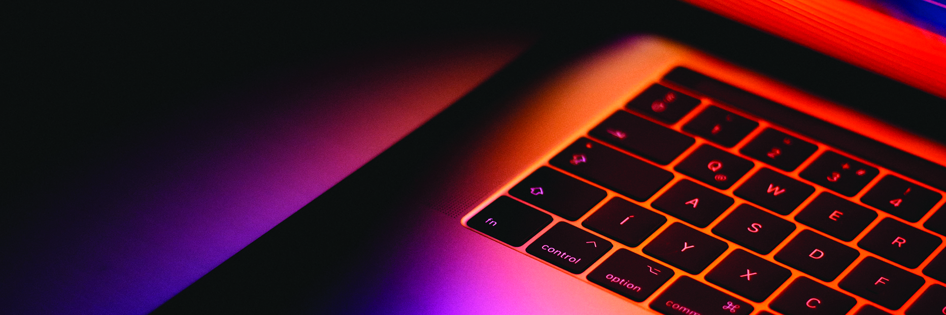 Half of a computer shown opening and glowing against a black background.