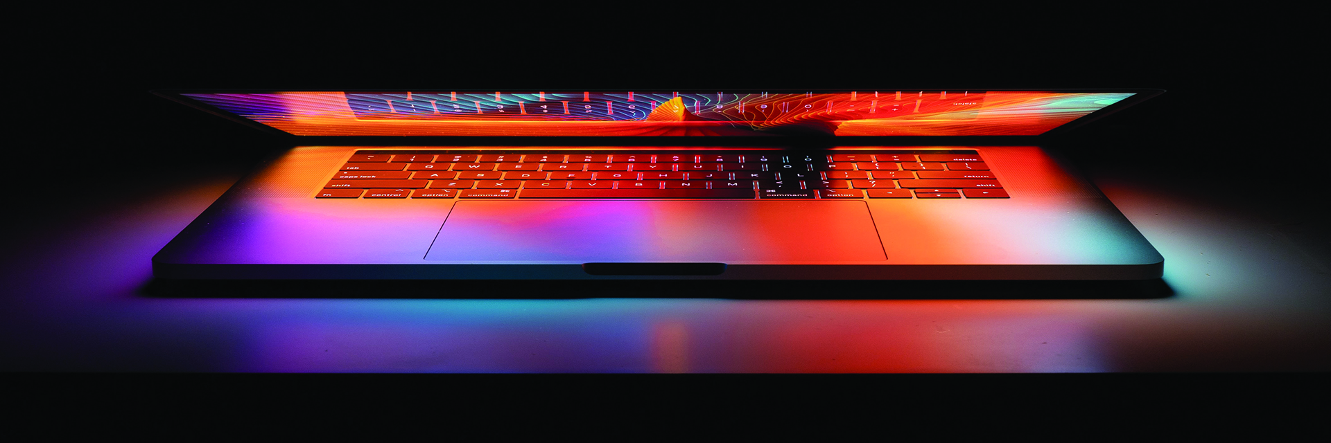 A glowing neon computer screen slightly open against a black background.