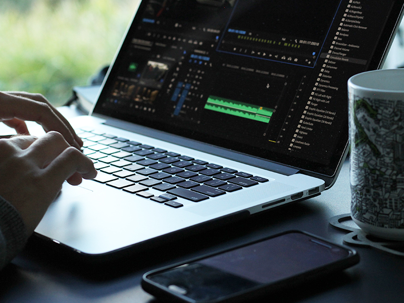 A person using a computer with Premiere Pro open to a project.
